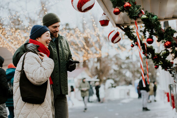 Obraz premium Korean woman and Caucasian man at winter market enjoying holiday decorations together