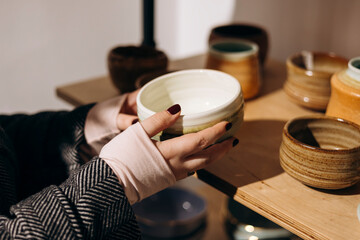 Woman touching handcrafted ceramics in cozy craft decor shop.