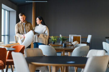 Obraz premium Couple choosing chair in modern furniture showroom