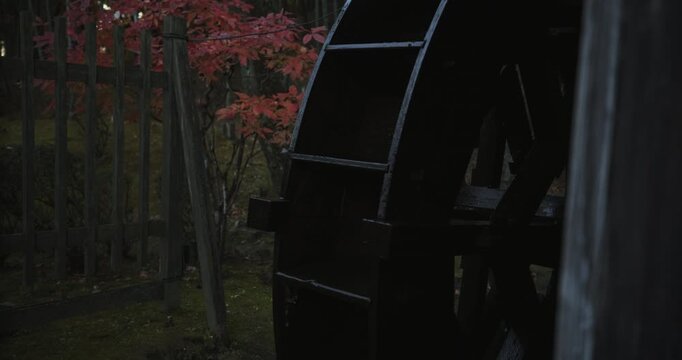 Water making beautiful, wooden, Japanese mill spin in autumn area at dusk