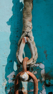 Weathered rope and rusty chain against blue surface