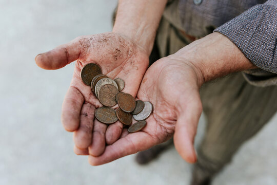 Hands holding a pile of old coins with dirt