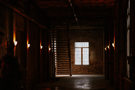 Dimly lit industrial loft with large window and stairs