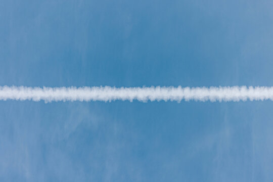 Airplane contrail across a clear blue sky