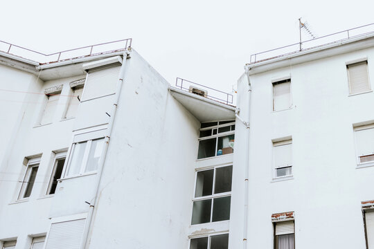 Old white apartment building exterior with closed windows
