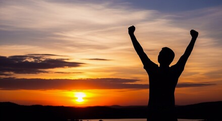 A silhouette of a triumphant man with arms raised at sunset