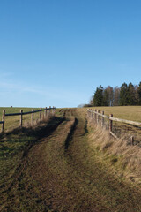 Fototapeta premium A dirt road with a fence on the side