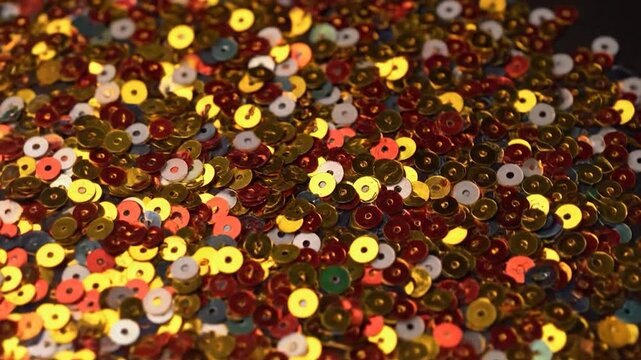 A close-up of a vibrant, scattered collection of circular shiny sequins in various colors