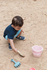 Toddler boy playing with sand toys outdoors