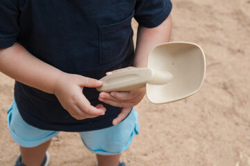 Child playing with toy shovel in sandbox