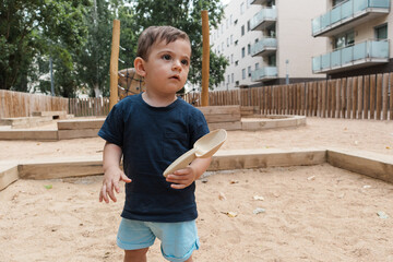 Toddler boy playing in sandbox with shovel