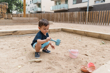 Toddler playing in sandbox with sand toys