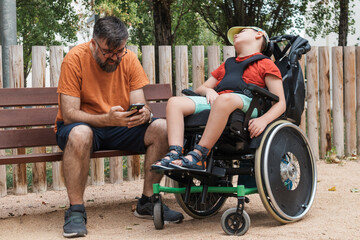 Father using smartphone next to son with cerebral palsy