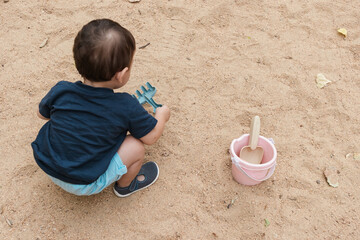 Toddler playing in sandbox with toys