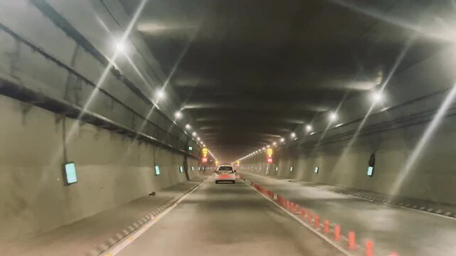 A vehicle driving through a long illuminated tunnel, symbolizing journey, infrastructure, and modern travel.