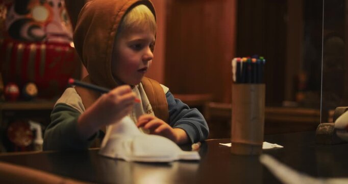 Cute kid using colorful pencils at desk - medium shot