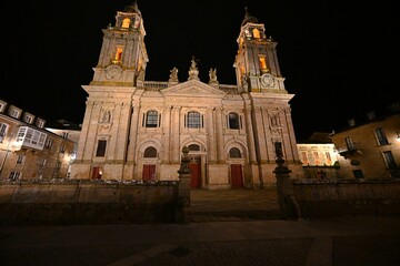 Fototapeta premium The illuminated facade of the Cathedral of Santa Maria in Lugo, Spain, photographed at night, reveals the majestic Gothic architecture and historical significance of this iconic church.