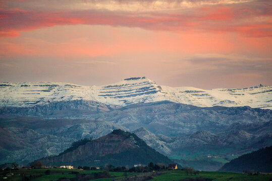 Snowy mountains of Pena Cabarga at sunset seen from the bay of Santander, scenic winter landscape