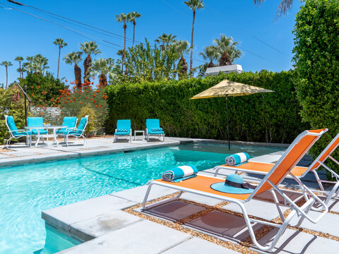 Swimming pool backyard with colorful chaise lounge chairs in daytime