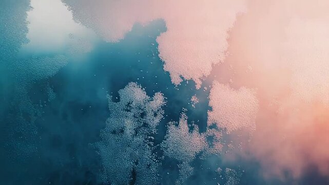 Abstract texture showing water droplets forming a frosted pattern on a glass surface, blending seamlessly between cool blue and warm peach tones, providing a dreamy, atmospheric background