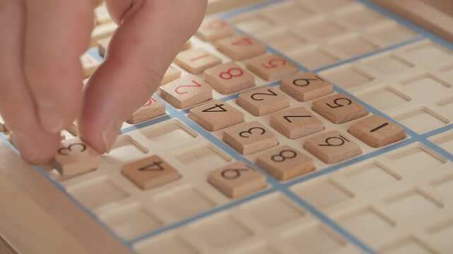 closeup hands carefully placing number into Sudoku puzzle, senior man focused on solving puzzle on wooden board, Brain exercise, cognitive health, and mental agility in mature age, brain health