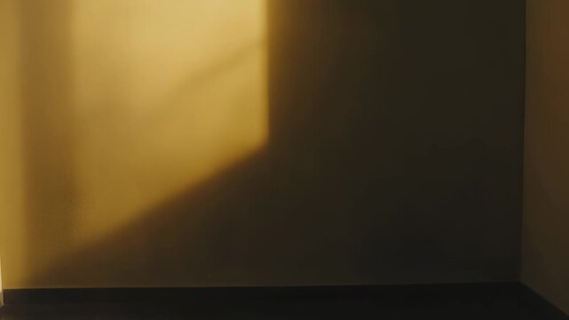 Golden sunbeam cuts across an interior wall corner, casting strong diagonal shadows and warm textured gradients for a minimal, geometric abstract composition