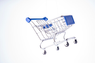 A shopping cart is suspended in midair. The cart is blue and silver. The cart is not on the ground. High quality photo