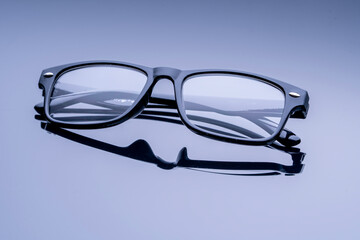 A pair of black eyeglasses with a white frame. The frame is slightly curved and the lenses are clear