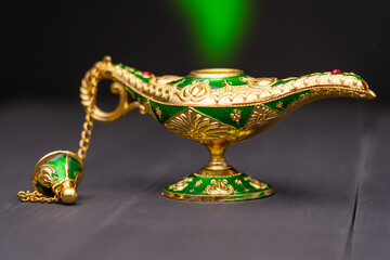 Precious golden magic lamp on blue background, fairy tales and wish fulfillment concept. High quality photo