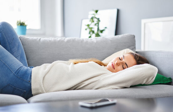 Beautiful young woman taking a peaceful nap and relaxing on sofa at home