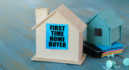 First Time Home Buyer. House figure, pen and notebook on white wooden table, top view