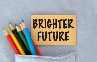 Brighter Future text on a sticker with colored pencils on a blue T-shirt background