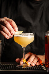 Preparing a margarita cocktail in a bar. Cold drink consisting of tequila, triple sec, and lime juice, served with salt on the rim of the glass.  Black background, vertical image.
