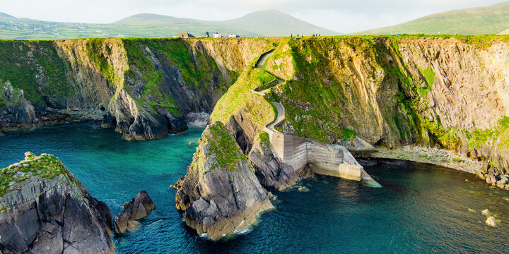 Dunquin or Dun Chaoin pier, Ireland's Sheep Highway. Aerial view of narrow pathway winding down to the pier, ocean coastline, cliffs. Popular location on Slea Head Drive and Wild Atlantic Way.