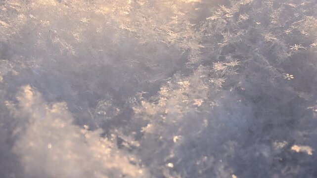 Abstract macro video of snow and ice crystals in warm sunlight. Shallow depth of field creates soft bokeh highlights. Natural winter texture, atmospheric background for seasonal and cinematic visuals.