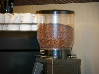 Selbstklebende Fototapeten Kaffeebohnen Grains de café dans un moulin professionnel lors d’une pause café en entreprise, espace de restauration lors d’un événement intérieur  © Colombe Delons