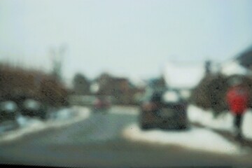 Abstraktes Motiv mit Schneebedeckter Wohnsiedlung in Kleinstadt und Frau mit roter Jacke auf Gehweg bei Frost, Eis und Schnee am Nachmittag im Winter