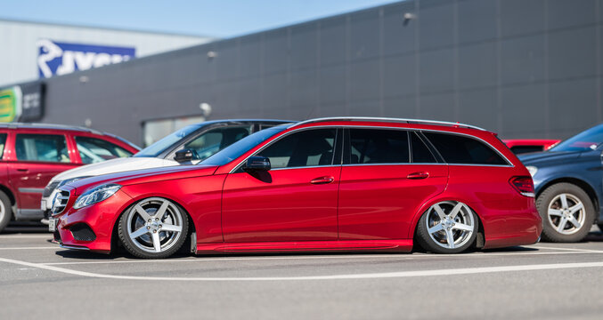 Gothenburg, Sweden - April 26 2025: Extremely lowered red 2014 Mercedes-Benz E 220 CDI station wagon at parking lot.