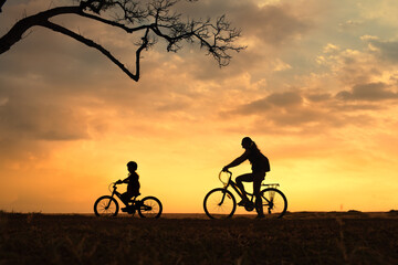 Obraz premium Parent and Child Riding Bicycles at Sunset 