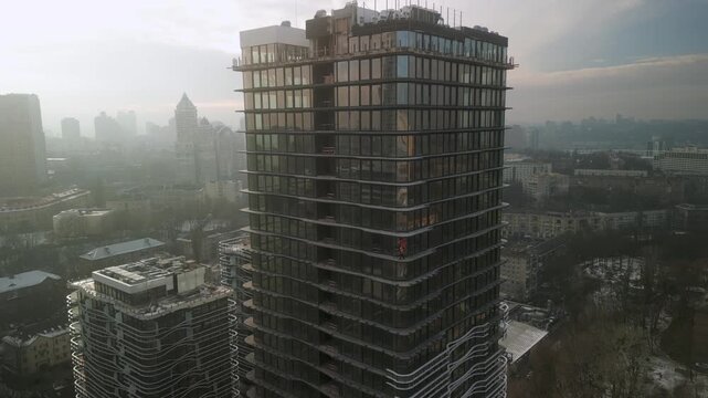 Drone view of industrial climbers in orange uniform and helmets working on high new modern building in European city