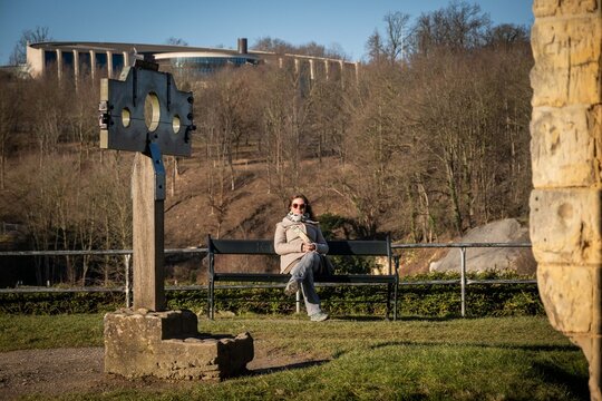 pillory stocks and visitor sitting on bench in Dutch ruins hilltop Castle Valkenburg aan de Geul, Limburg, Netherlands. Historic landmark monument popular tourist educational sightseeing attraction