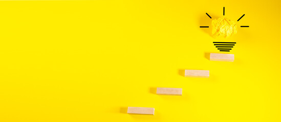 Creative idea and innovation concept. Wooden blocks with light bulb on yellow background.