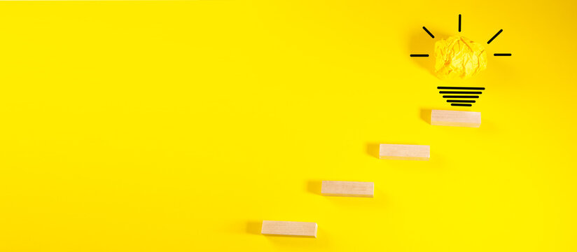 Creative idea and innovation concept. Wooden blocks with light bulb on yellow background.