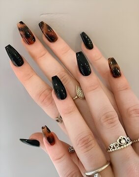 Woman displays her hands featuring black and brown painted nails
