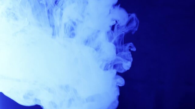 Billowing clouds of colorful smoke swirl and mix against a dark background. Vibrant blue, purple, and red hues shift with dynamic glitch transitions and signal noise effects.