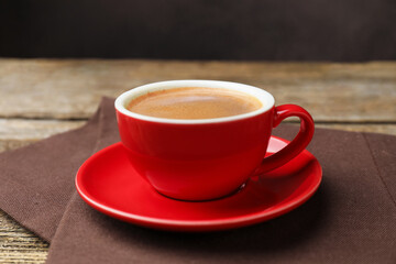 Obraz premium Cup with aromatic coffee and napkin on wooden table, closeup