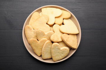 Delicious heart shaped butter cookies on dark wooden table, top view