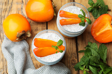 Chia seed pudding with persimmons and mint on wooden table, flat lay