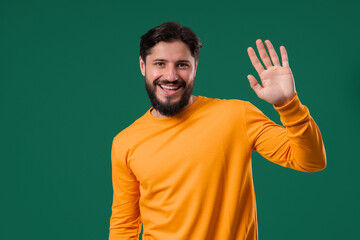 Friendly 30s aged man Waving Hand - Hello, Hi, salute, chao. Greetings on green © kohanova1991
