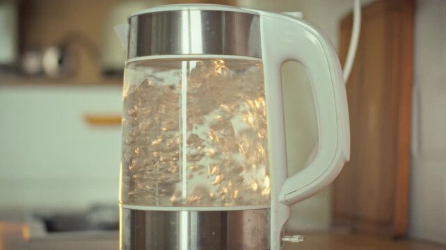 In modern kitchen, electric kettle heat-resistant glass body visibly demonstrates boiling process, as heated water releases warmth, forming rising bubbles surface, exemplifying effect applied heat